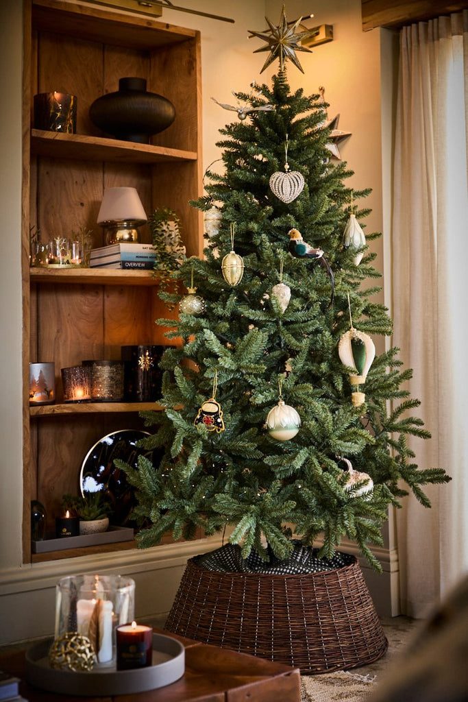 Christmas tree with range of decorations next to a wooden shelf containing a range of home decor items including vases lanterns candle holders and christmas gifts