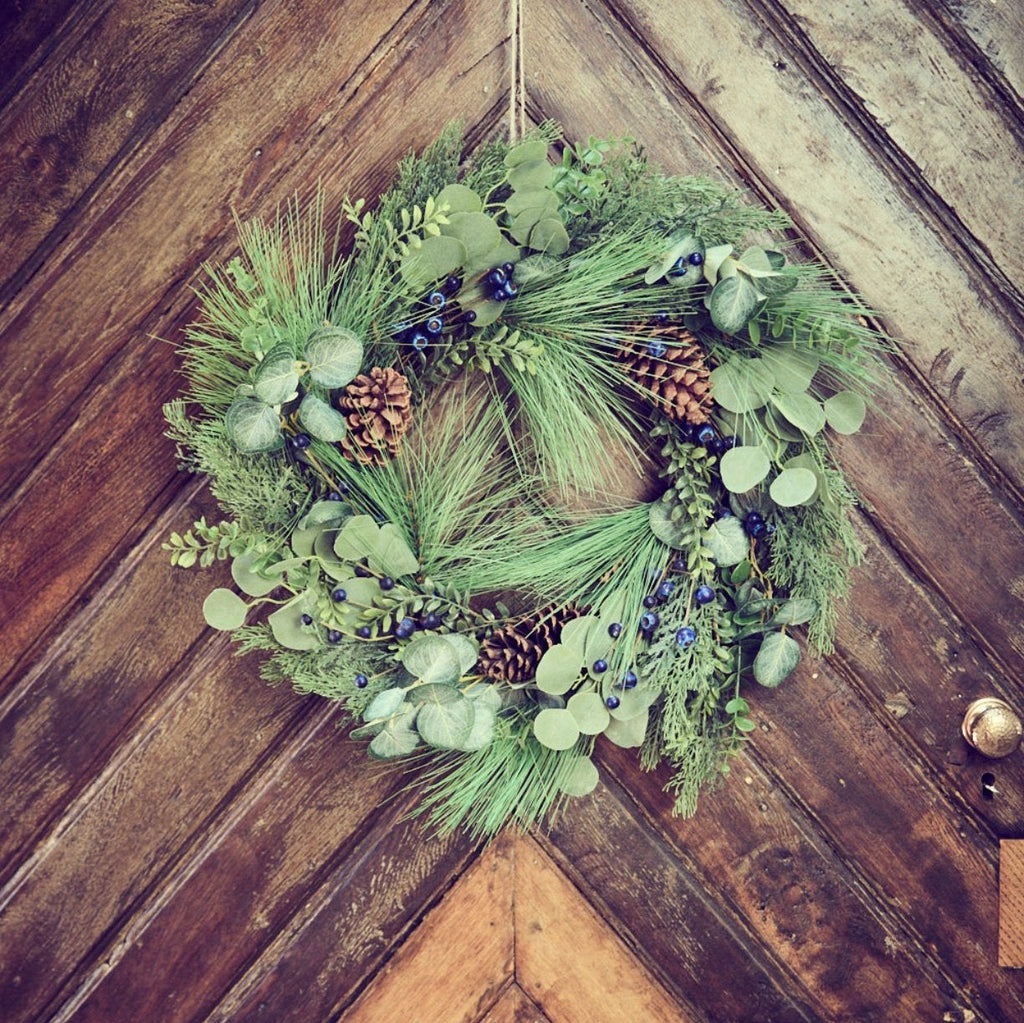 Pinecone and blueberry wreath on a wooden door