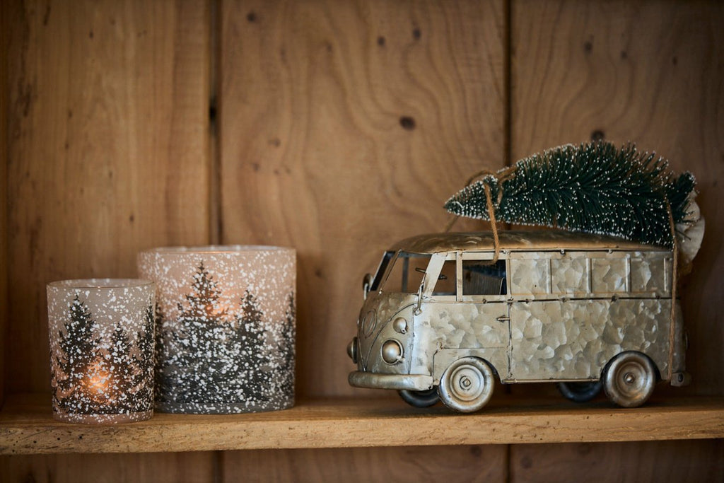 Campervan decoration on a wooden shelf with snowflake and fir tree candle holder