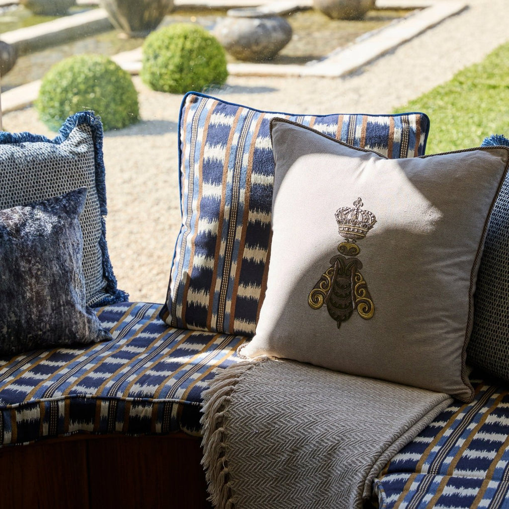 Close up of window seat with bee cushion and crown and blue complementary cushions in the sunlight