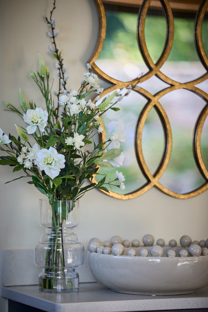 Cream bobble bowl on a side board next to a faux flower arrnagement and mirror